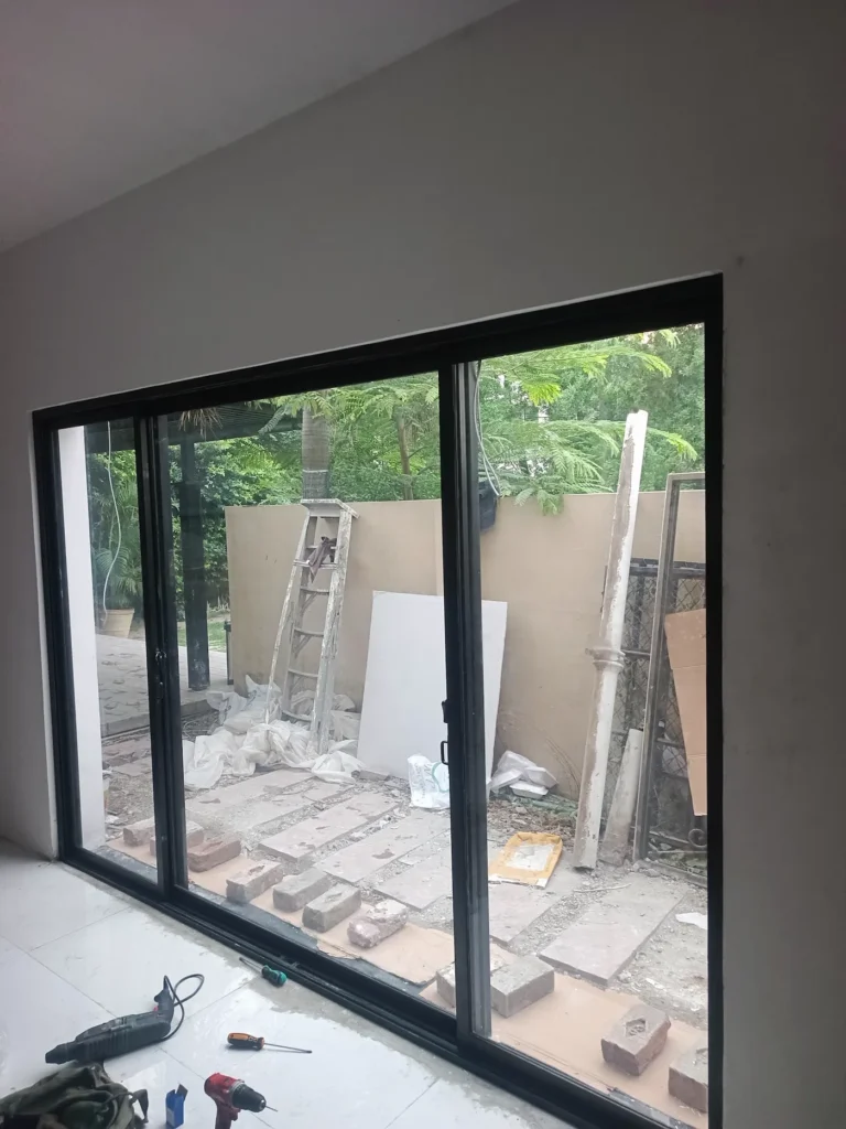 Black aluminum sliding glass doors installed in a residential room in Lahore