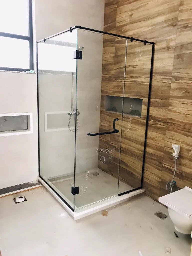 Frameless glass shower cabin with black fittings in a tiled bathroom